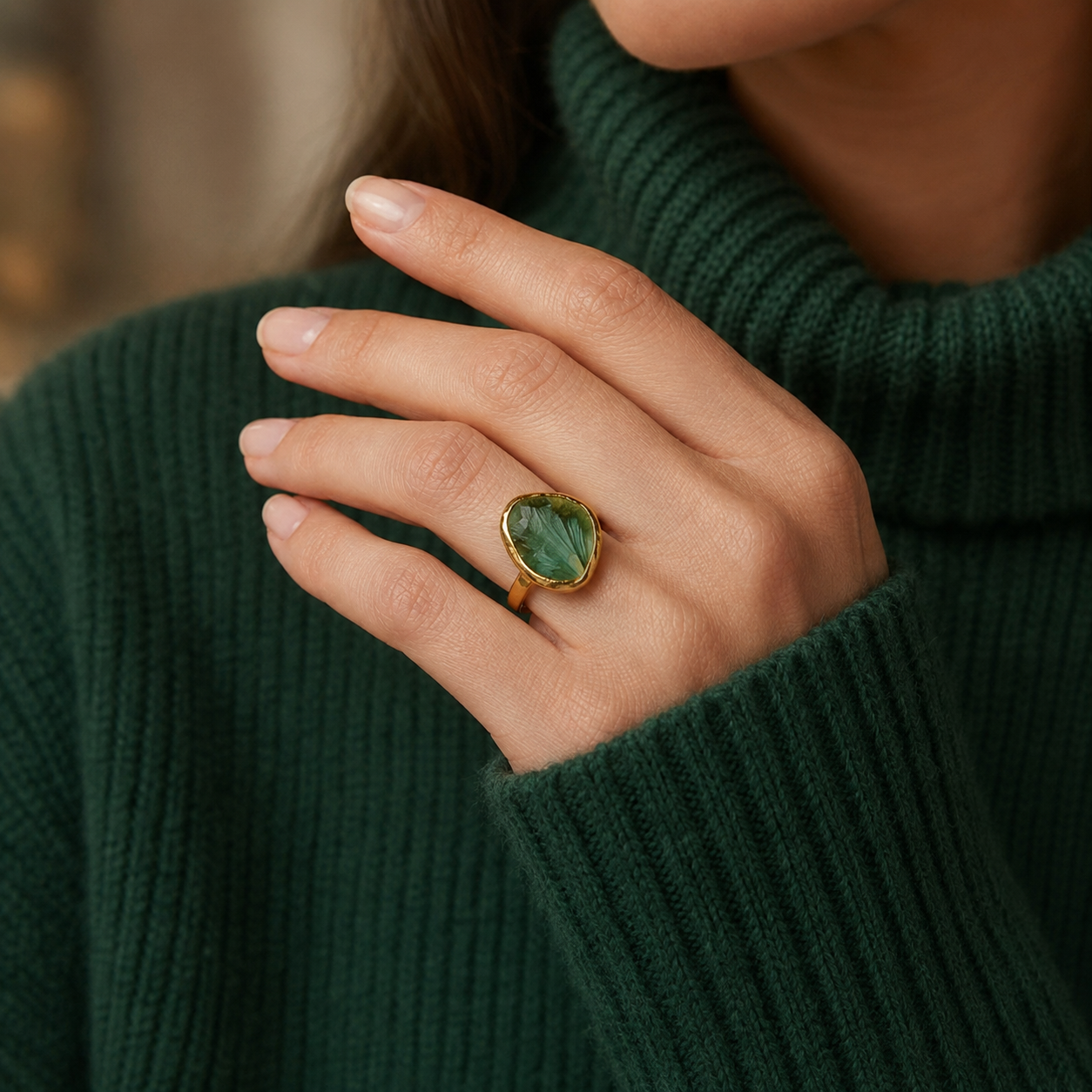 Woman wearing a gold-vermeil rough green tourmaline statement ring with a dark green sweater.