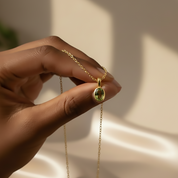 Close-up of hand holding an oval cut August Peridot birthstone bezel pendant necklace with a gold chain, highlighting the gemstone clarity and refined setting. Custom birthstone necklace designed in a minimalist style, ideal for layering. Personalized gemstone jewelry gift for her, suitable for Valentine’s Day, birthdays, or sentimental keepsake gifting.