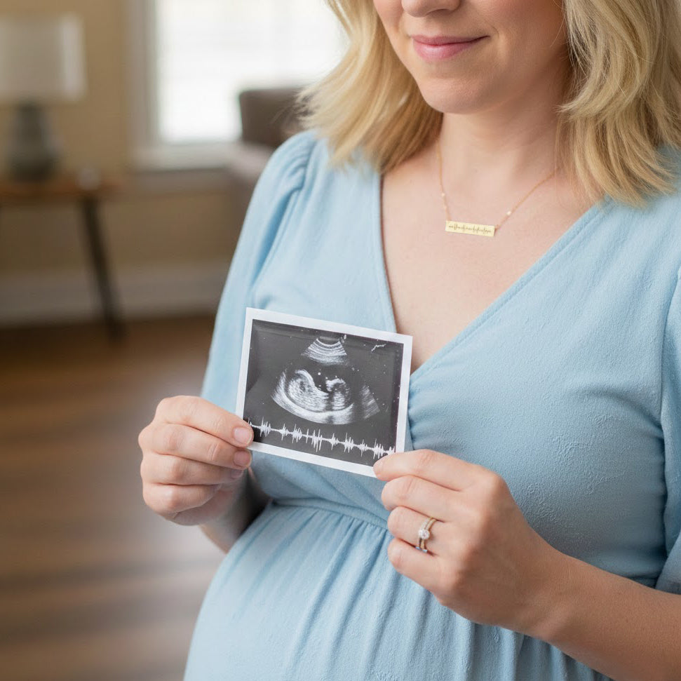 A mom wearing a gold engraved heartbeat necklace holds up a photo of her babys ultrasound and sonogram. Each necklace is crafted with sentimentality and care in mind, and can be created with your personalized photograph. Gift for New Mom