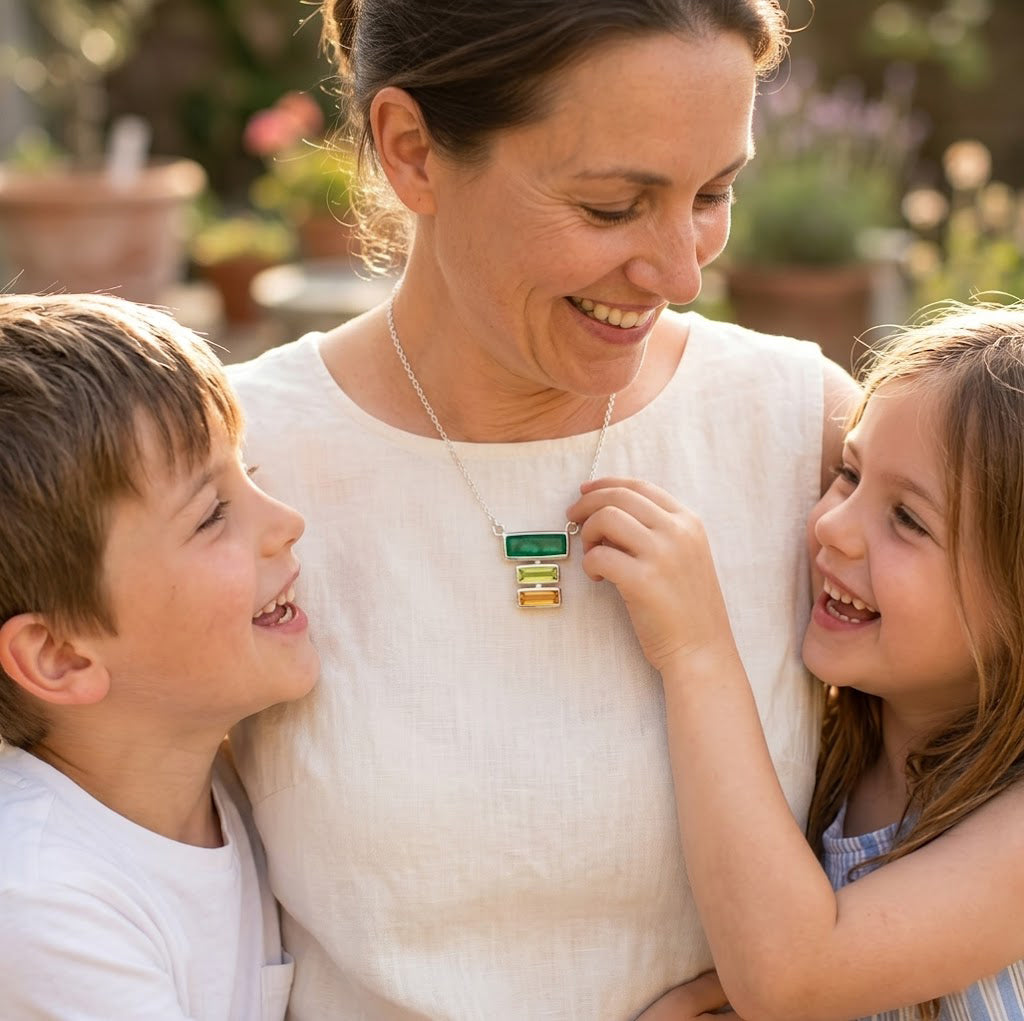 Personalized mother’s birthstone necklace featuring three horizontal baguette stones in green, yellow, and clear gemstone colors.