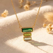 Custom birthstone mom necklace with stacked baguette gemstones representing mom and children on a delicate gold chain.