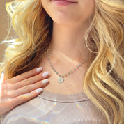 Layered look featuring personalized initial disc pendant necklace on gemstone wire-wrapped chain paired with dainty gold chains. Engraved letter charm creates a meaningful, customizable gift for moms, daughters, wives, and friends. Elegant, minimalist jewelry ideal for everyday wear, stacking, and special occasions such as Mother’s Day or birthdays.