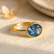 Elegant oval kyanite ring with a sapphire-blue cabochon-style faceted stone in a slim 18k gold vermeil bezel setting; minimalist September birthstone ring designed for everyday wear, stacking, promise or anniversary gifting; handmade by Danique Jewelry; available in multiple US sizes; gift-ready packaging included.