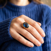 Woman wearing a large blue Kyanite gemstone ring with a dark blue sweater.
