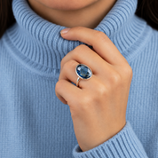 Woman wearing a large Kyanite September birthstone ring in sterling silver with a blue sweater.
