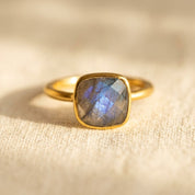 Cushion cut labradorite ring in gold bezel setting with iridescent blue flash gemstone