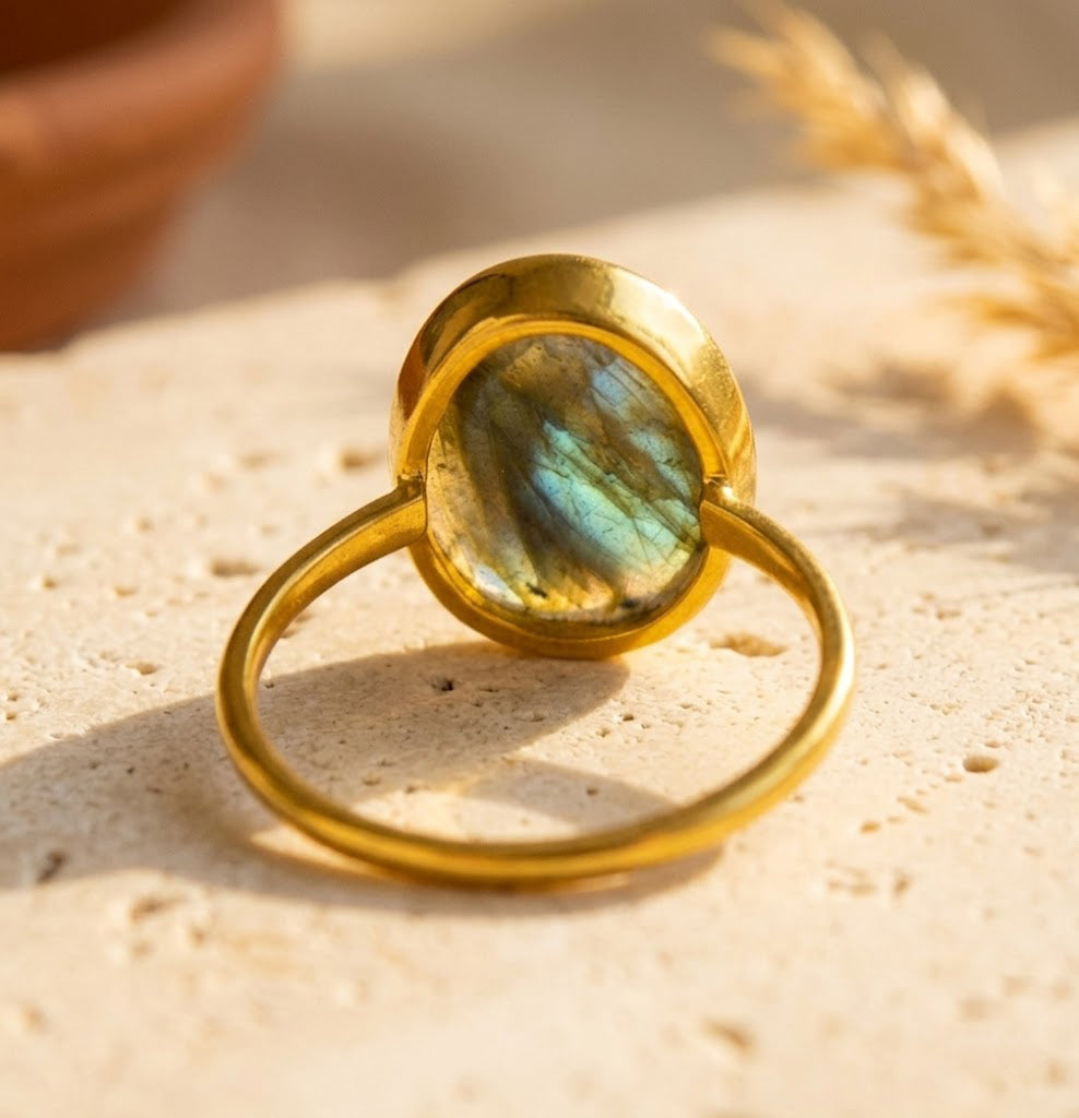 Close-up labradorite ring in gold vermeil on soft fabric, showing oval gemstone setting and natural blue flash.