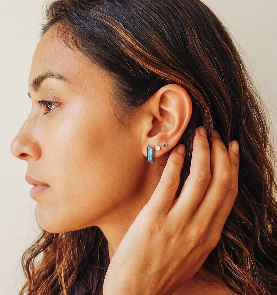 Woman wearing tiny baguette birthstone stud earrings close up