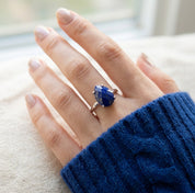 Hand wearing a sterling silver lapis lazuli teardrop ring with faceted blue gemstone and delicate prong setting.