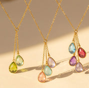 Lariat teardrop birthstone necklace for mom featuring multiple gemstones in sterling silver, gold filled, and rose gold. Personalized family jewelry with dangling charms for children and loved ones. Choose from January Garnet, February Amethyst, March Aquamarine, April Clear Quartz, May Emerald, June Pearl, July Ruby, August Peridot, September Sapphire, October Opal, November Citrine, or December Blue Topaz. A meaningful gift for Mother’s Day or Christmas.