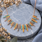 Mixed metal Sunray fringe necklace with turquoise gold silver and rose gold bars on gray stone

