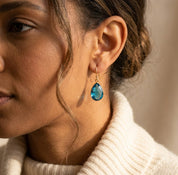 Close-up of London blue topaz teardrop earrings on ear, dainty blue gemstone drop earrings in gold filled