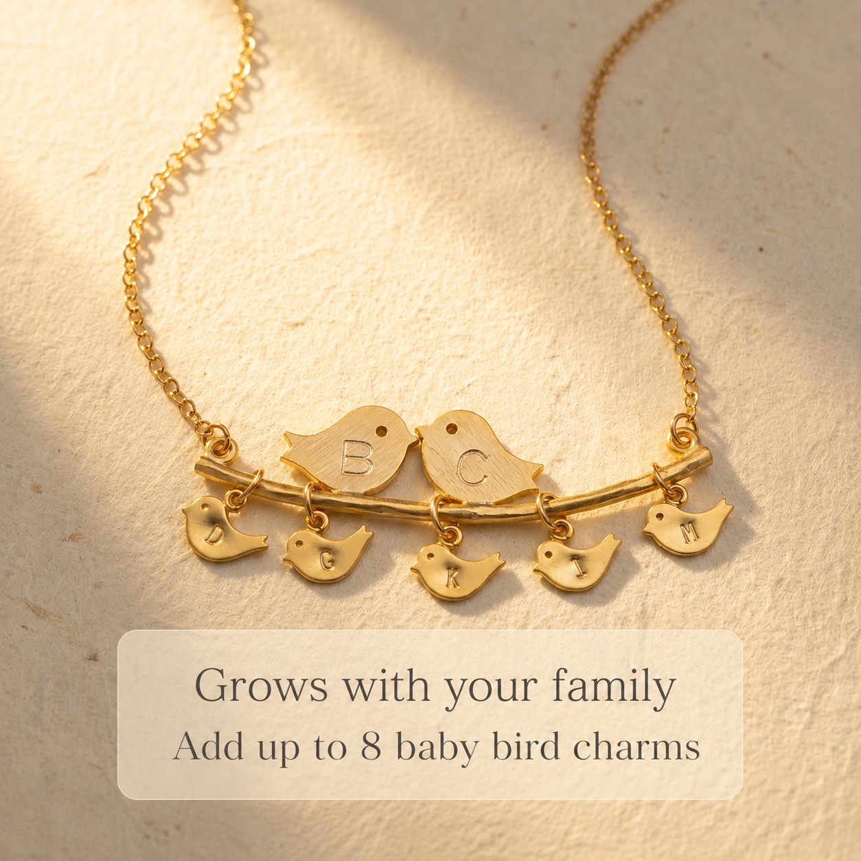 Gold lovebirds necklace with multiple initial baby bird charms designed to grow with a family.