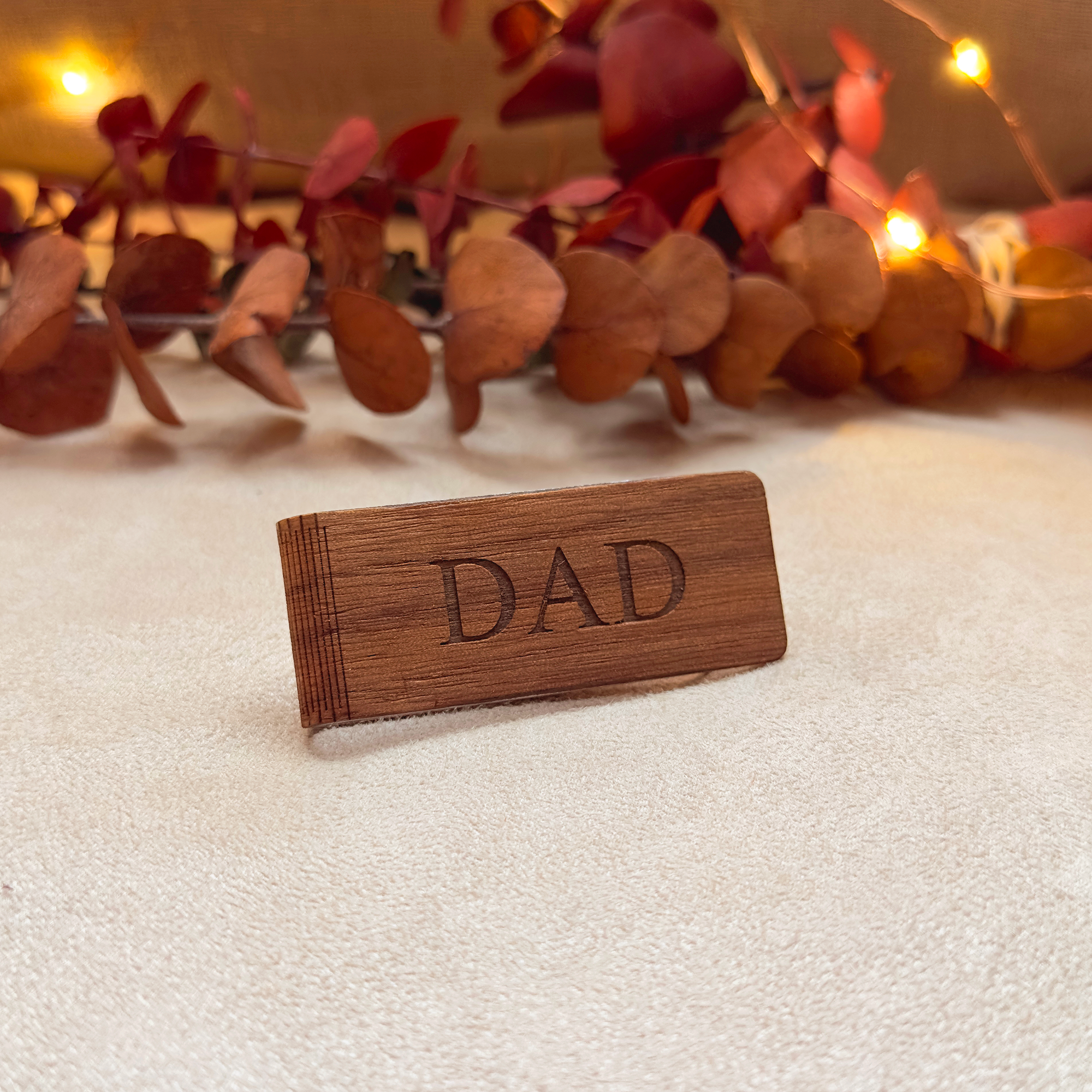 Mahogany wood money clip engraved with “DAD,” displayed with warm holiday lights. A thoughtful Christmas or Father’s Day gift, also suitable for birthdays and special occasions. Handcrafted from sustainably sourced wood, personalized to order, and ready for gifting in a Danique Jewelry box.