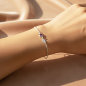 Model wearing dainty birthstone name bracelet with one gemstone and engraved charm.