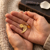 Close up of custom angel wing necklace with birthstone and engraved initial