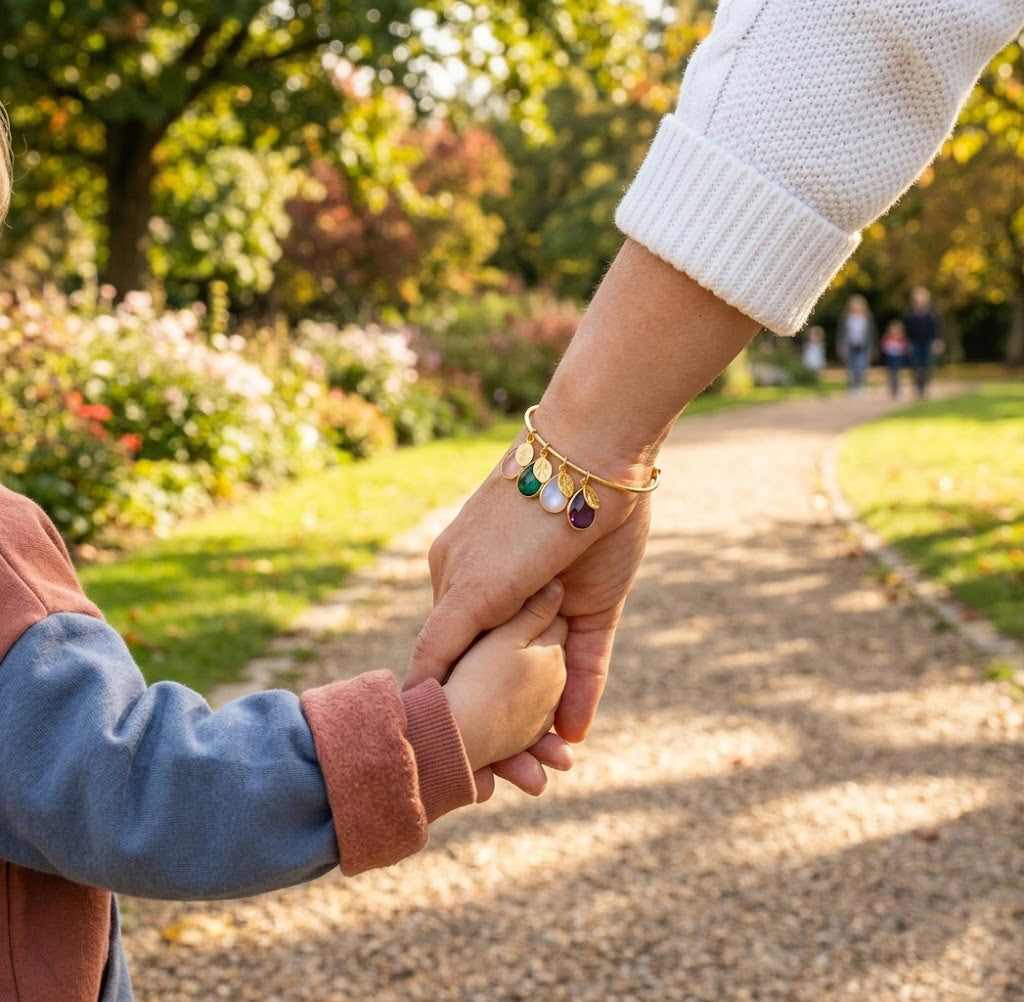 Close up gold bangle bracelet with multiple birthstone charms and engraved initials custom mom jewelry