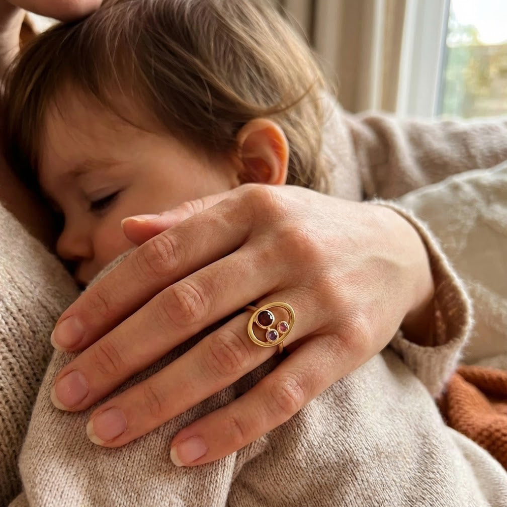 mother and baby wearing custom birthstone ring for mom, meaningful family jewelry with children birthstones january garnet february amethyst march aquamarine