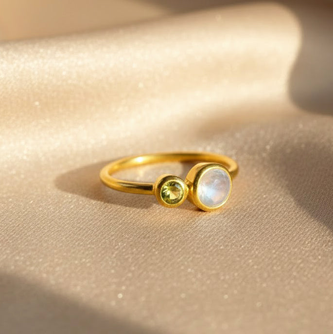 Minimalist gold double birthstone ring with June moonstone and August peridot on champagne satin, personalized mom ring representing children’s birthstones