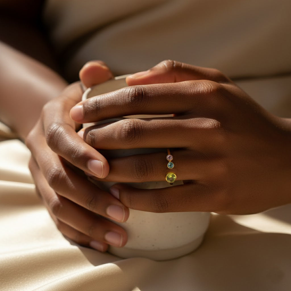 Minimalist mom birthstone ring styled with coffee, custom family jewelry featuring garnet, amethyst, aquamarine, and emerald stones, adjustable open ring design representing children’s birth months in a meaningful keepsake.