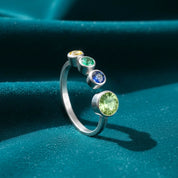 Personalized birthstone ring for mom of three, featuring an adjustable open gold band with one 5mm bezel-set center birthstone and three surrounding 3mm child stones in vibrant colors. Beautifully photographed for a warm, elegant look that highlights the craftsmanship. A perfect family jewelry gift for Mother’s Day, birthdays, holidays, or celebrating a new mom of three children with a meaningful keepsake she can wear daily.