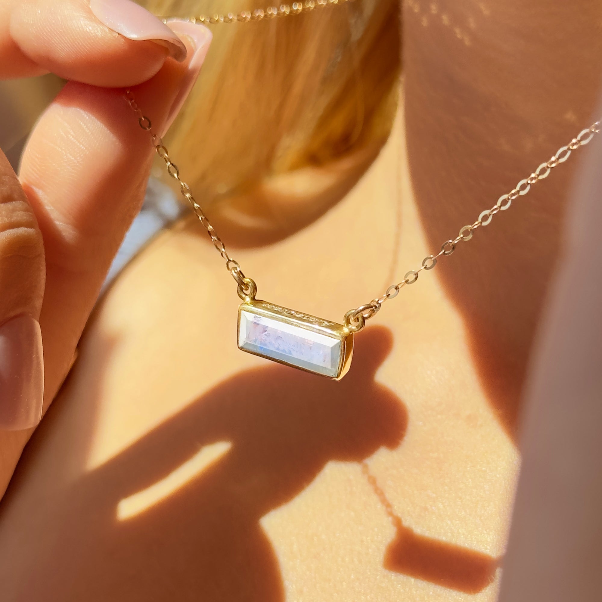 Dainty personalized moonstone bar necklace worn on model, showcasing iridescent gemstone in a 14k gold filled bezel setting with optional custom engraving for a meaningful birthstone gift. Ideal for moms, daughters, bridesmaids, and women who love minimalist jewelry, this handcrafted gemstone bar pendant offers elegant sparkle for birthdays, anniversaries, and everyday style. Available in sterling silver, gold filled, or rose gold filled.