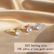 Dainty oval moonstone ring shown on a model’s hand with a soft blue sweater, styled as an everyday June birthstone ring.