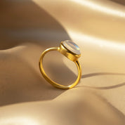 Stackable oval gemstone rings featuring rainbow moonstone and other colorful birthstones in gold settings.