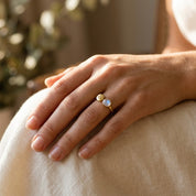 Adjustable moonstone and initial ring worn on the hand in warm natural light.