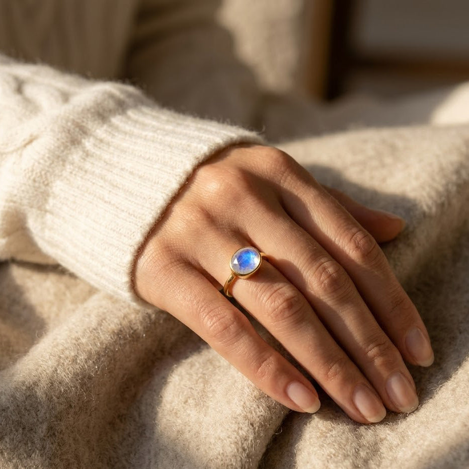 Hand wearing oval bezel set moonstone ring in gold vermeil with natural rainbow moonstone
