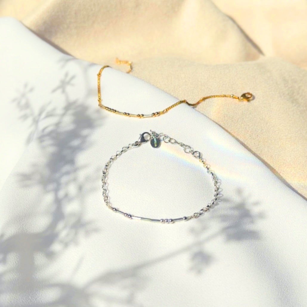 two delicate bracelets, one gold and one silver, with small beads spaced evenly along the length of each bracelet. Pinky promise. Morse code bead jewelry, morse code beaded jewelry, secret message jewelry, bff jewelry, bff bracelet, pinky promise bracelet, secret message bracelet, hidden message jewelry, hidden message bracelet, sterling silver, gold, adjustable bracelets, delicate bead bracelet, new, delicate pattern of dots and dashes bracelet, lobster clasp, dainty bracelet, couples jewelry