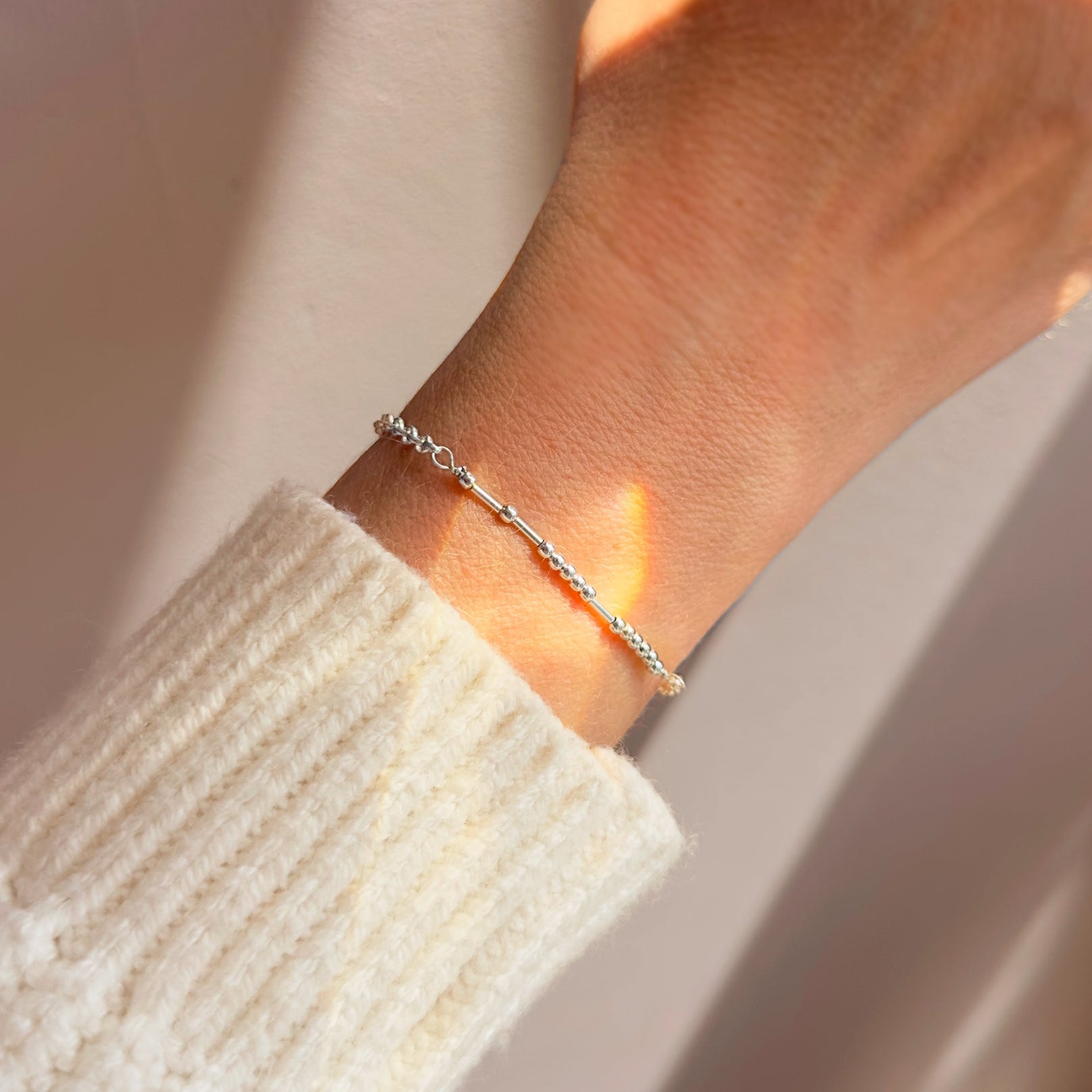 A dainty Morse code bracelet on wrist in sterling silver, featuring hidden message beads that spell a secret word. Adjustable and minimalist, this bracelet is a thoughtful gift for girlfriend, boyfriend, or best friend. Perfect for birthdays, Christmas, anniversaries, Valentine’s Day, or everyday wear. Handcrafted in sterling silver, gold filled, or rose gold filled.