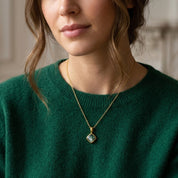 close up of natural gemstone pendant with bezel setting on gold chain, showcasing texture and stone detail