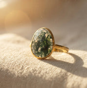 Natural moss agate teardrop ring in yellow gold vermeil photographed in sunlight with dark green organic inclusions