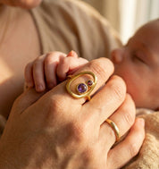 New mom wearing personalized mother child birthstone ring while holding baby’s hand.
