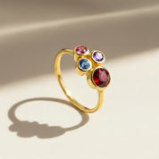 Single gold plated custom mother of three birthstone ring. Mom stone is January Garnet, kid's stones are October pink tourmaline, September  sapphire and February Purple Amethsyt.