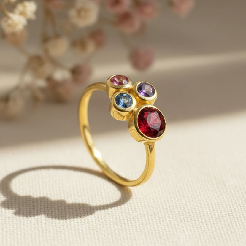 Single gold plated custom mother of three birthstone ring. Mom stone is January Garnet, kid's stones are October pink tourmaline, September  sapphire and February Purple Amethyst.