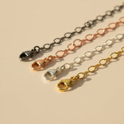 Close-up of necklace extenders in gold, silver, rose gold, and oxidized black, showcasing lobster clasp detail. Adjustable chain extension for necklaces and bracelets, adding 1–6 inches. Perfect minimalist jewelry accessory for everyday wear or gifting occasions.