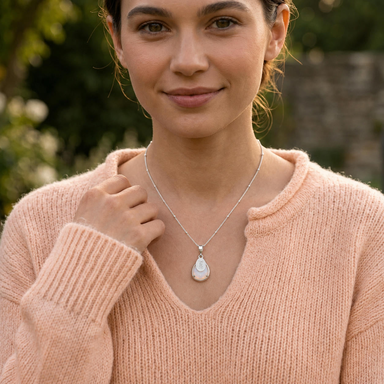 Gold opalite name necklace worn by a model in a peachy color sweater with 16 inch chain length.