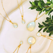 Luminous opalite necklaces with round and teardrop pendants displayed on a white ceramic dish with greenery. Handmade opal gemstone jewelry in gold symbolizing hope and creativity, perfect minimalist accessory for layering or everyday elegance. Meaningful October birthstone jewelry for women — a delicate and unique gift for birthdays, weddings, or special celebrations, beautifully crafted by Danique Jewelry.
