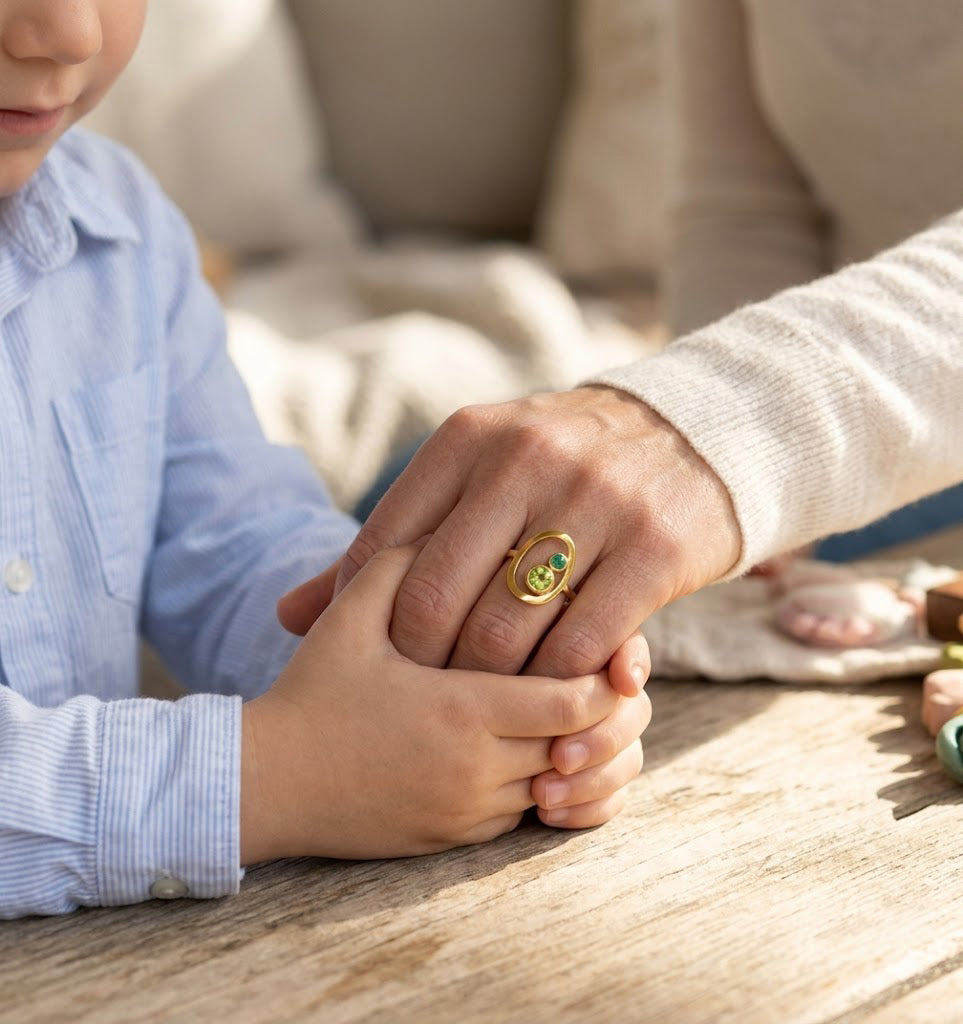 Gold mother and child birthstone ring worn on moms hand in warm natural light.