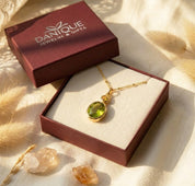Elegant two birthstone pendant necklace with a large green gemstone and small gold birthstone charm, perfect for everyday sentimental jewelry. Shown in Danique Jewelry Box