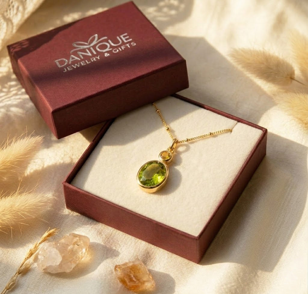 Elegant two birthstone pendant necklace with a large green gemstone and small gold birthstone charm, perfect for everyday sentimental jewelry. Shown in Danique Jewelry Box