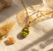 Custom two birthstone necklace with one larger green birthstone and one smaller golden birthstone on a delicate gold chain, perfect for new moms or meaningful gifts.
