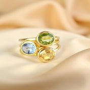 Stack of oval birthstone rings in 14k gold vermeil with bezel-set hydro gems—Aquamarine (March), Peridot (August), and Citrine (November). Dainty stacking rings with faceted stones and slim bands; minimalist, gift-ready jewelry.