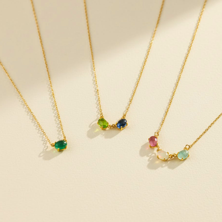 Horizontal oval birthstone necklace featuring custom multi-stone family jewelry design with dainty oval bezel gemstones, shown with emerald quartz, blue topaz, peridot, amethyst, and moonstone stones. Personalized mom necklace ideal for child name engraved gifts, Mother’s Day, birthdays, or Christmas gifting. Handmade in gold, rose gold, or sterling silver and perfect as a sentimental necklace for mom, grandma, or a new mother celebrating her children.