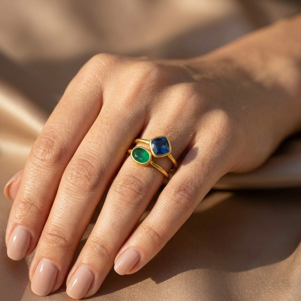 Woman wearing green and blue gemstone stacking rings in yellow gold vermeil in warm natural light