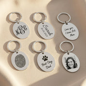 Custom engraved oval keychains displayed in multiple personalization styles including monogram, handwritten messages, photos, and signature engravings. Features durable stainless steel construction with optional double-sided engraving, ten available font styles, and support for handwriting, drawings, fingerprints, or memorial notes. Ideal personalized gift for husbands, wives, parents, grandparents, or best friends for birthdays, anniversaries, Christmas, and Father’s or Mother’s Day.