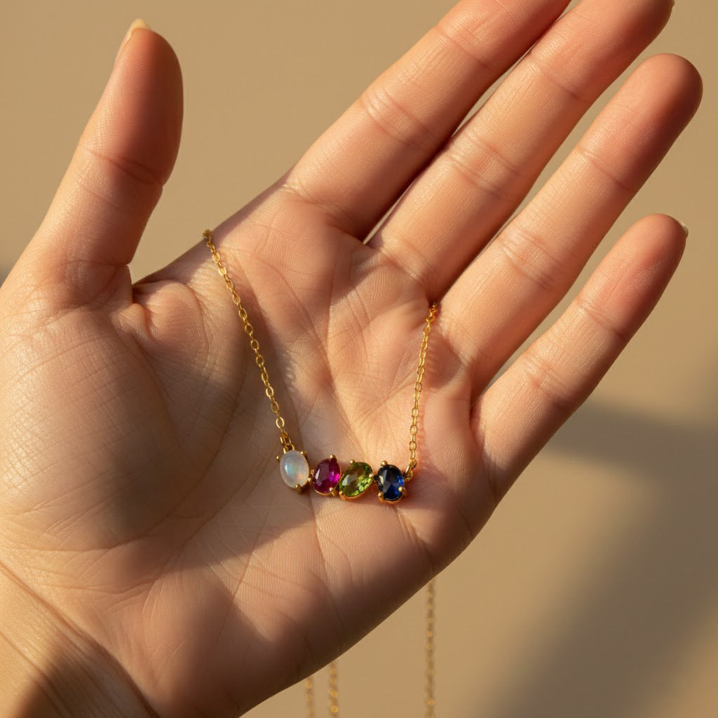 Hand holding custom oval cabochon birthstone necklace with multiple gemstones symbolizing children or loved ones. Personalized family necklace designed as a meaningful mom gift, grandma gift, or sentimental birthstone jewelry.
