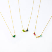 Three gold filled oval prong set cabochon stone necklaces. First necklace features  single green onyx stone. The middle necklace has peridot and kyanite birthstones. Final necklace features ruby, moonstone and aqua chalcedony birthstones. 